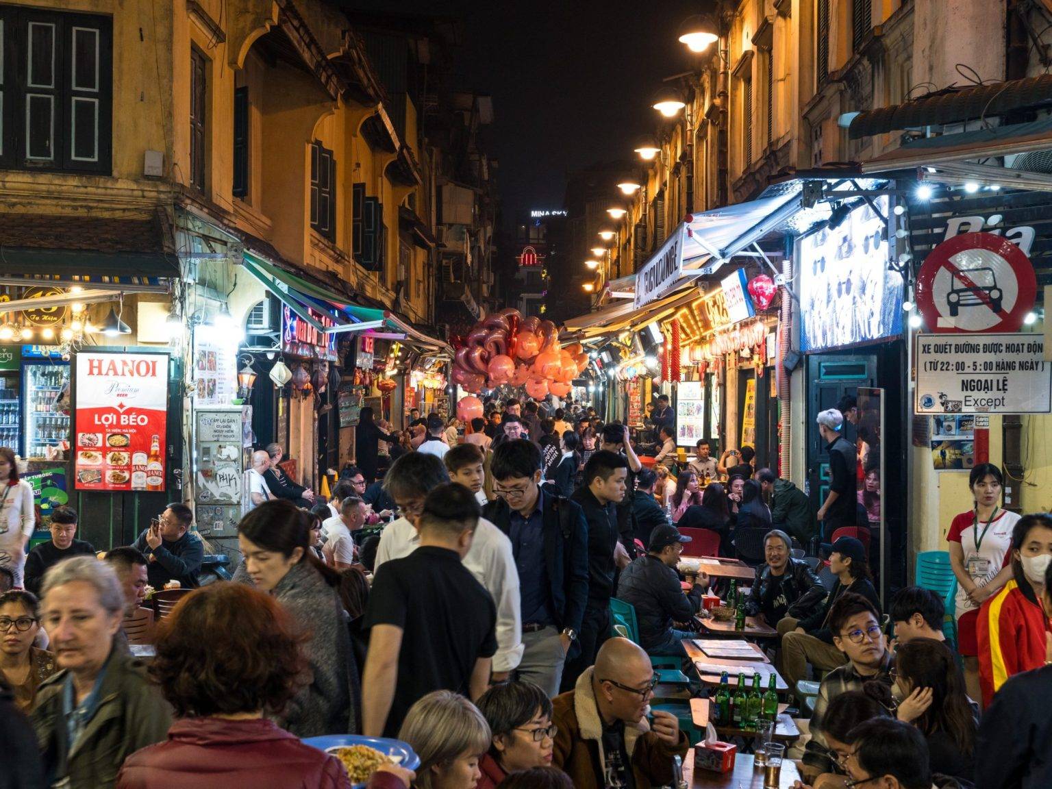 Die Ta Hien Beer Street bei Nacht voller leuchtender Schilder und Menschen.