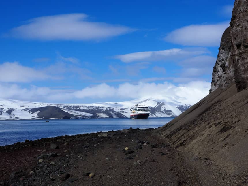 Auf der Antarktis im Wasser bei Deception Island schippert ein großes Schiff durchs Wasser.