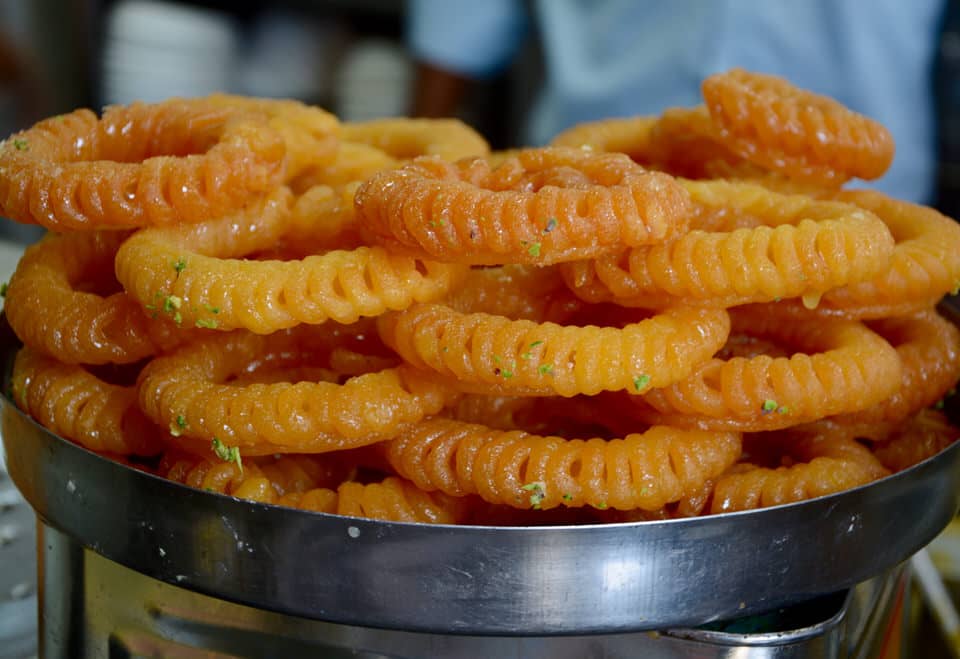 Spiralförmig goldgelb-gebackene Jalebis sind in Shiv Misthan Bhandar auf einem silbernen Tablet angerichtet.