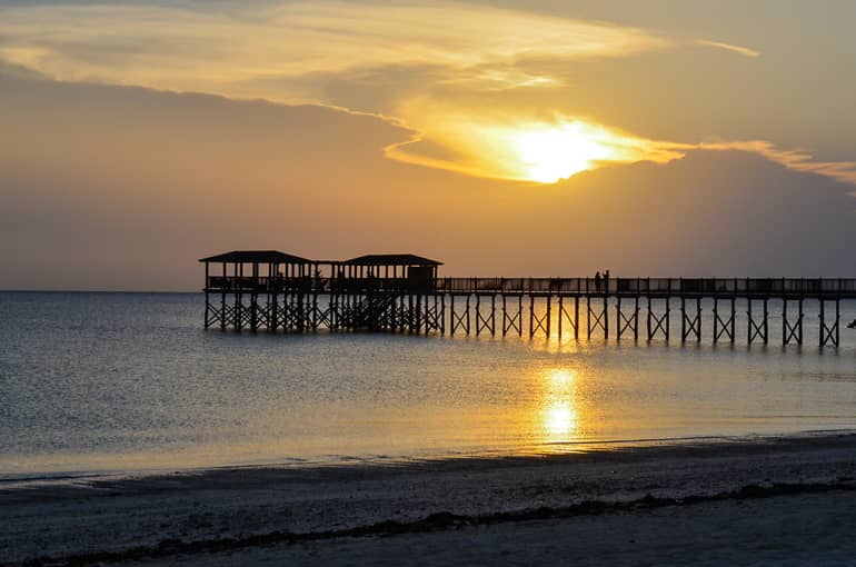 Sonnenuntergang auf Tansanias Sansibar, vom Strand des The Residence Zanzibar führt einer hölzerner Steg mit Pavillion ins Meer.
