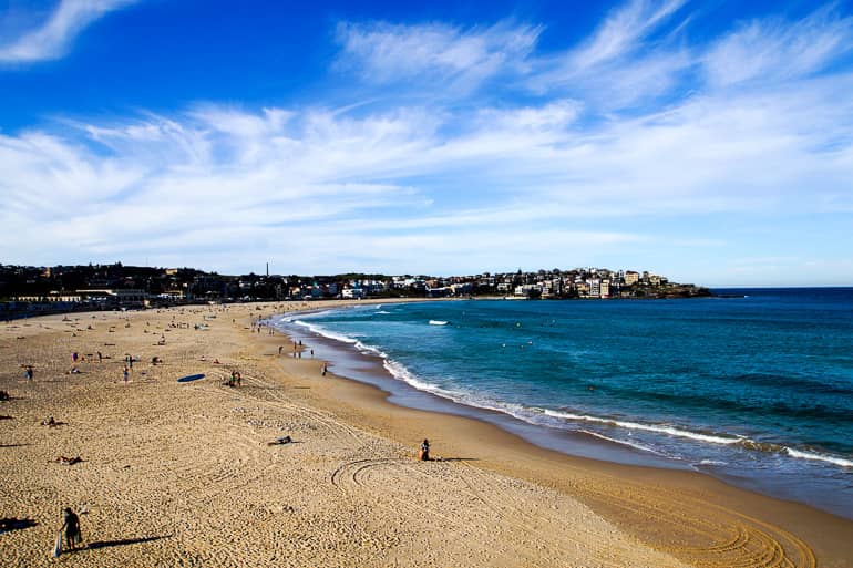 Vereinzelt genießen Besucher am Strand vom Bondi Beach, Australien das strahlende Wetter und die Aussicht über das türkisfarbene Meer.