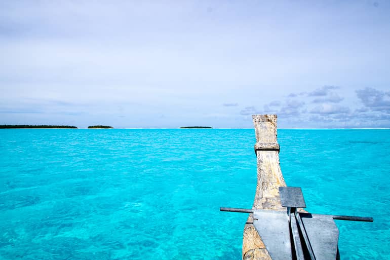Ein hölzernes Vaka schippert auf dem hellblauen Meer auf Aitutaki, Cookinseln.