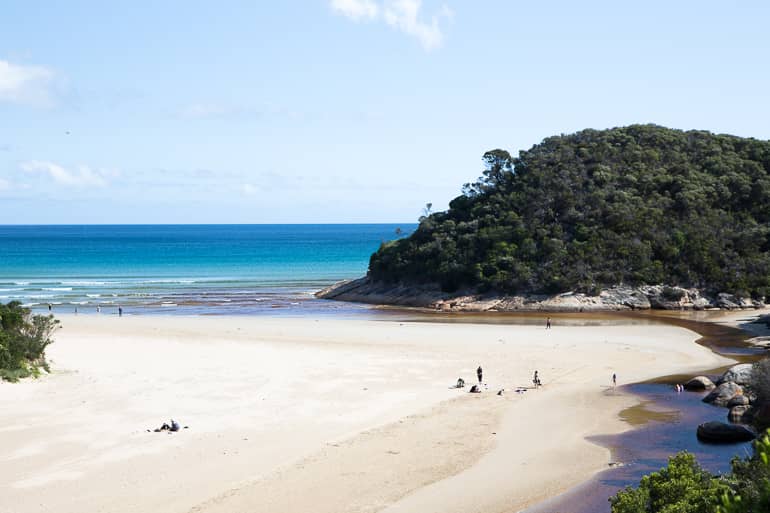 In Yarra Valleys Wilsons Promotory fließt der Tidal River ins Meer, vereinzelt befinden sich Menschen am feinen Sandstrand.