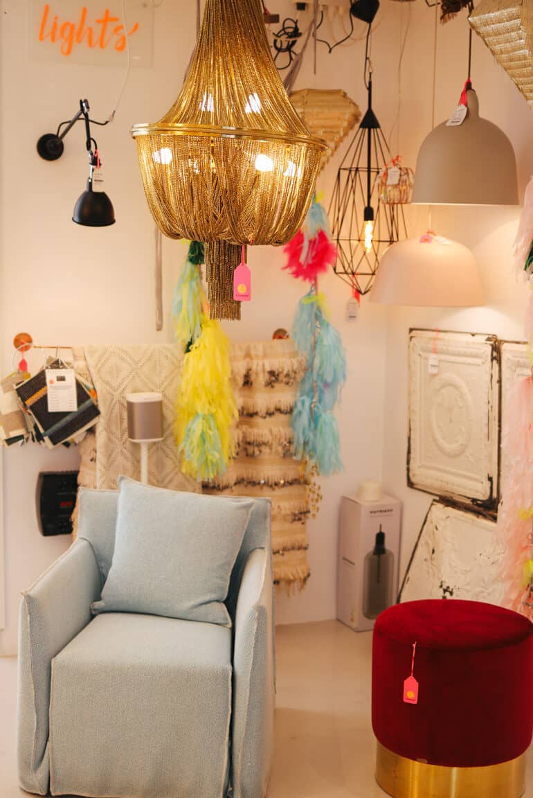 Ein goldener Lüster, sowie allerlei ausgefallene Lampen hängen über einem Sessel im BConnected Store von Santa Catalina Palma.