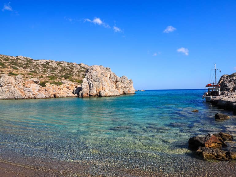 Angelehnt an einer Felsformation in der abgeschiedene Alimoúnta-Bucht in Karpathos hat ein kleines Segelschiff Rast eingelegt.
