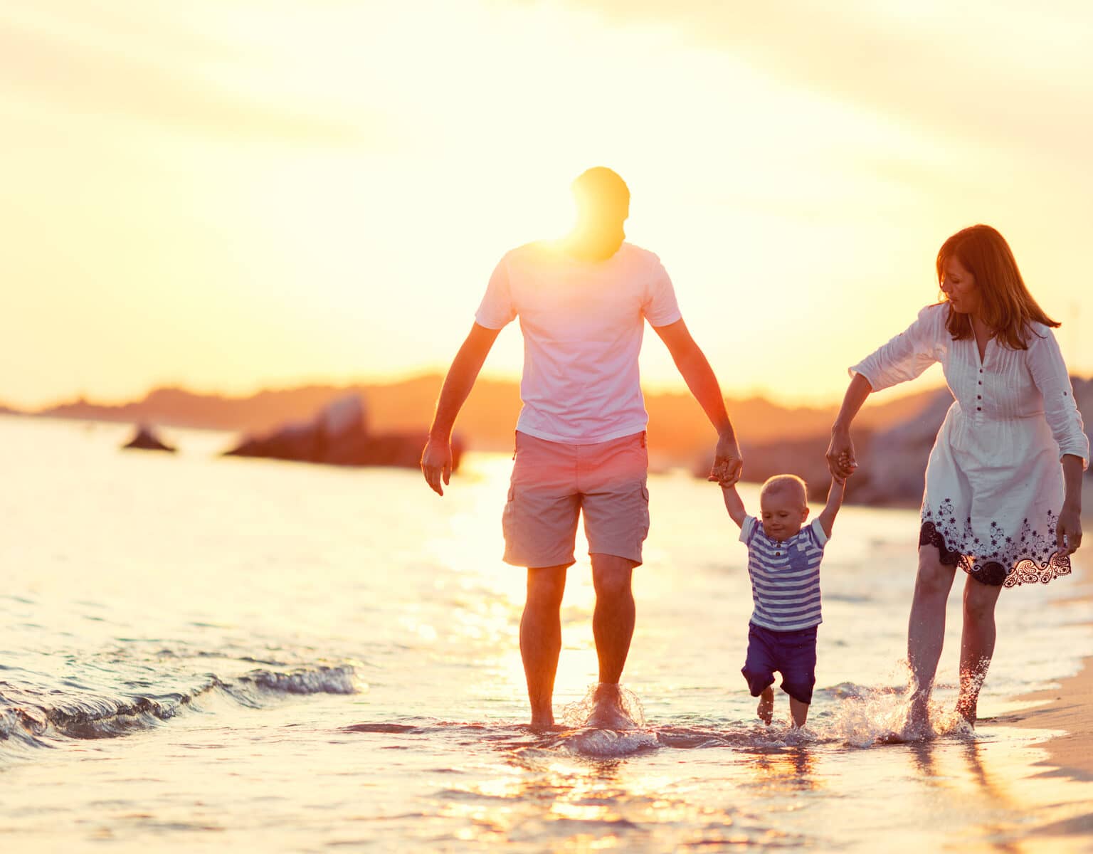 Elternzeit Reisen: Mutter und Vater mit Baby am Strand