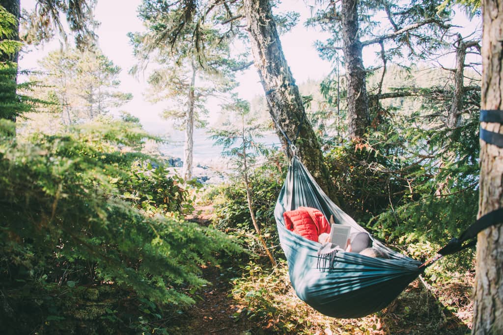 Vancouver Island: Eine Person liegt in einer Hängematte, mit einem Buch in der Hand.