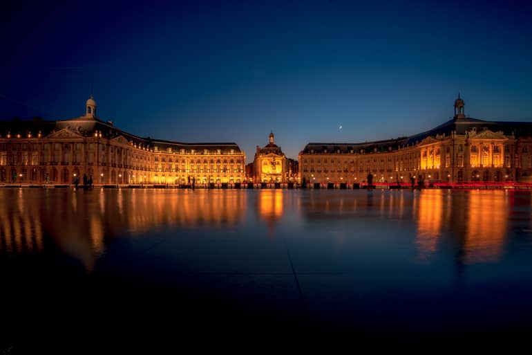 Die angestrahlten Gebäude spiegeln sich wunderschön zur blauen Stunde.