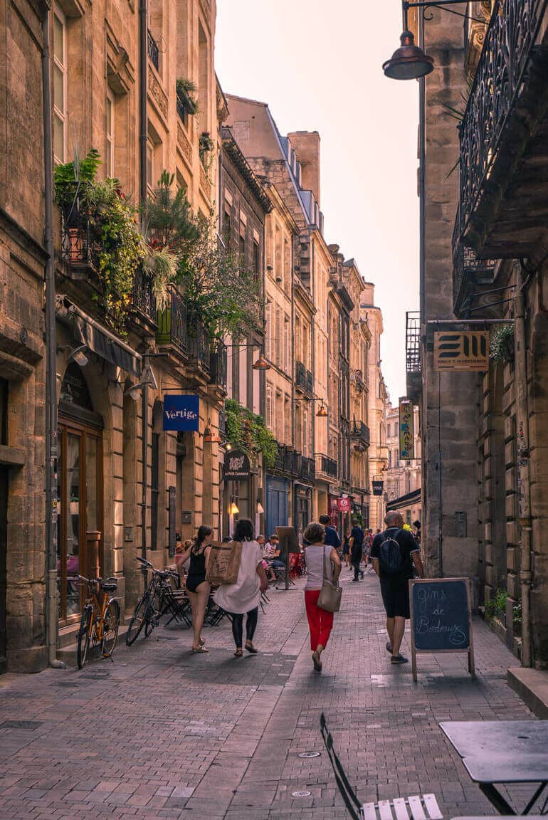 Städtetrip: Eine Gasse mit vielen alten Gebäuden und einigen Menschen.