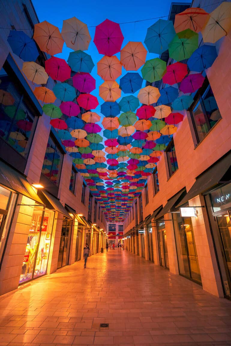 Städtetrip: Die Einkaufsgasse am Abend, mit den bunten Regenschirmen an der Decke.