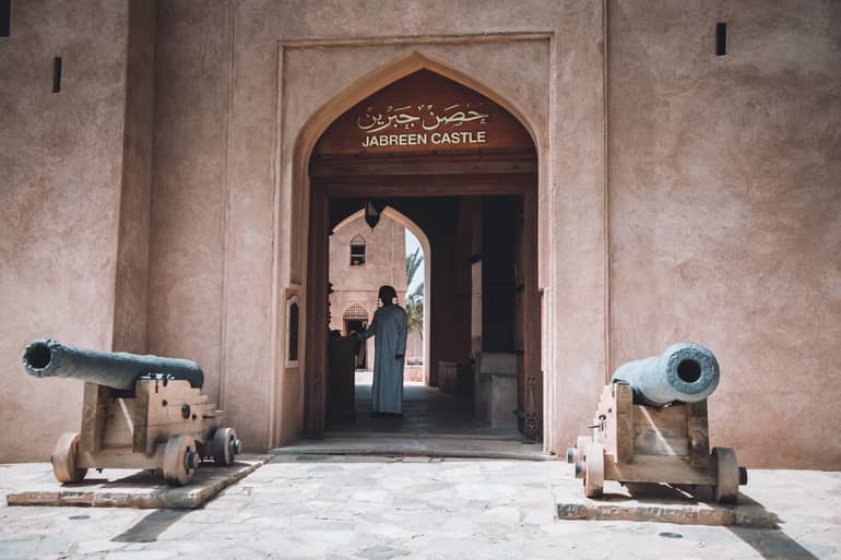 Oman Roadtrip; Reiseroute: Ein Thor zu einer Burg in der ein Mann steht.