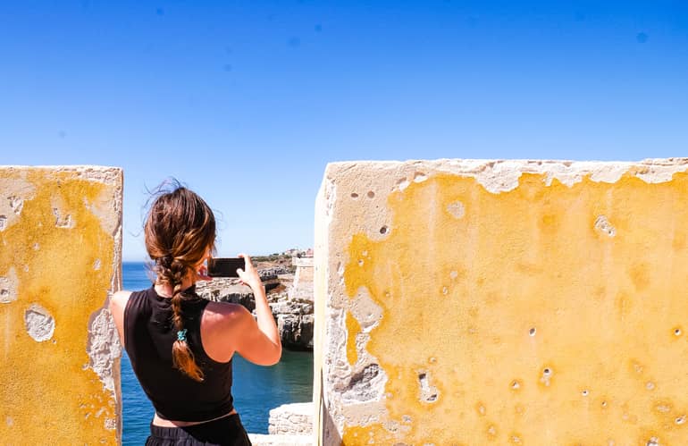 Eine Frau zwischen zwei gelben Mauern eines Forts in Peniche, Portugal.