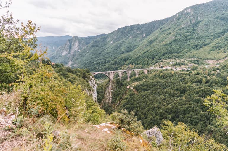 Die runden Bögen der Tara-Brücke erstrecken sich über der Schlucht und verbinden die grün bewaldeten Berge ringsherum.