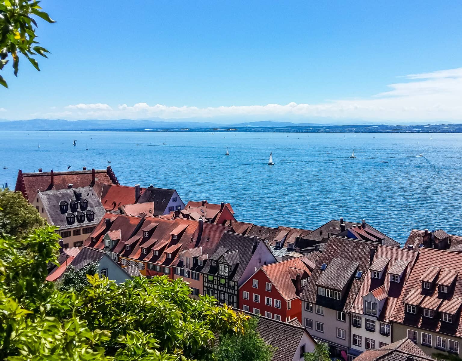 Der Blick über die Häuserdächer auf den Bodensee lässt ein paar vereinzelte Segelboote erkennen.
