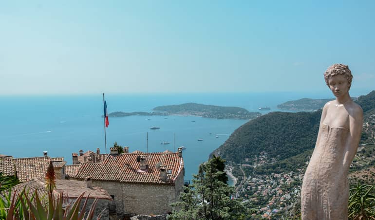 Eine Statue die auf einem Berg steht und das Meer im Hintergrund ist.