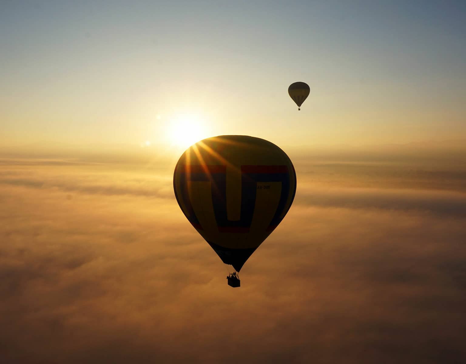 Ein Heißluftballon fliegt über den Wolken von Mexiko, genauer gesagt über den Pyramiden von Teotihuacán in die Abendsonne.