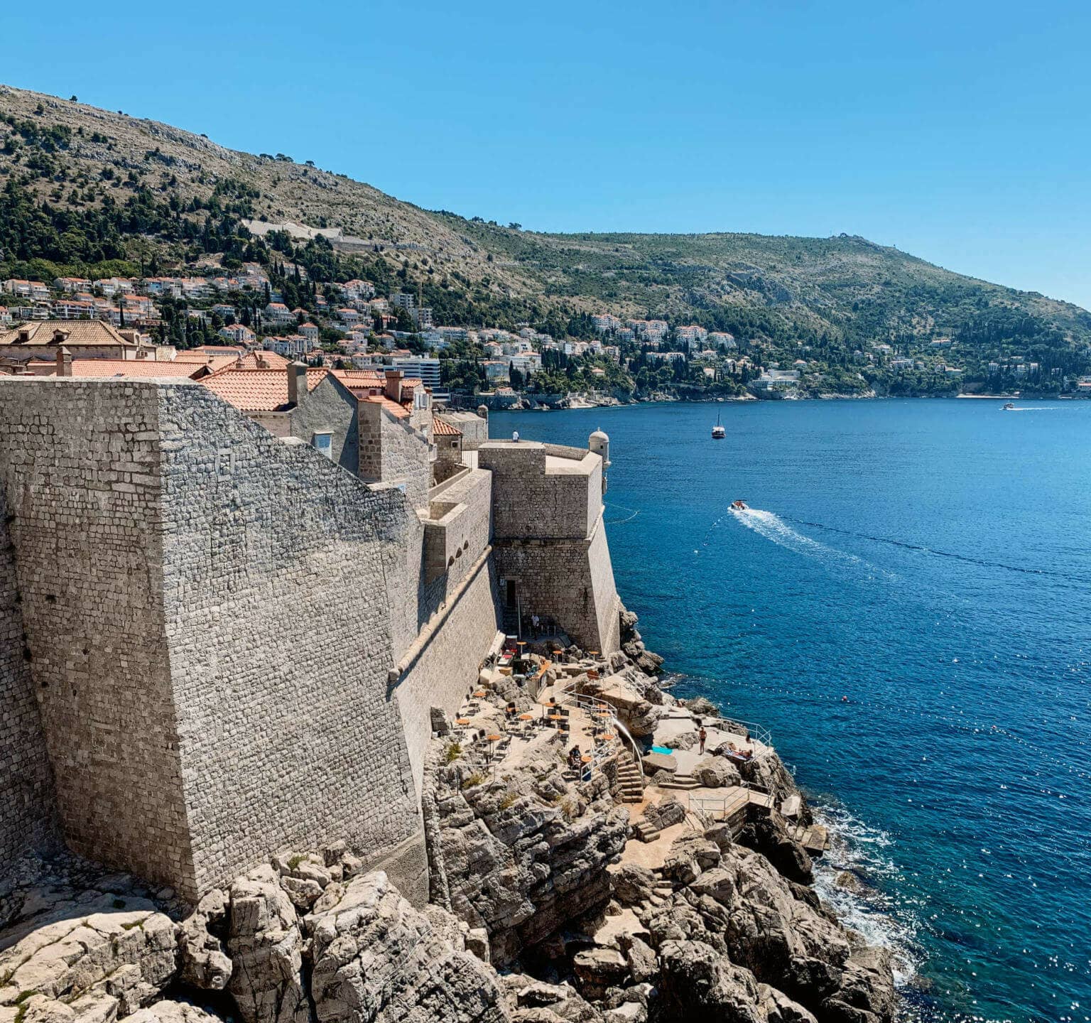 Vom Café Buža aus hat man einen traumhaften Blick auf die direkt an der Küste gebauten Festungsmauern von Dubrovnik, Kroatien.