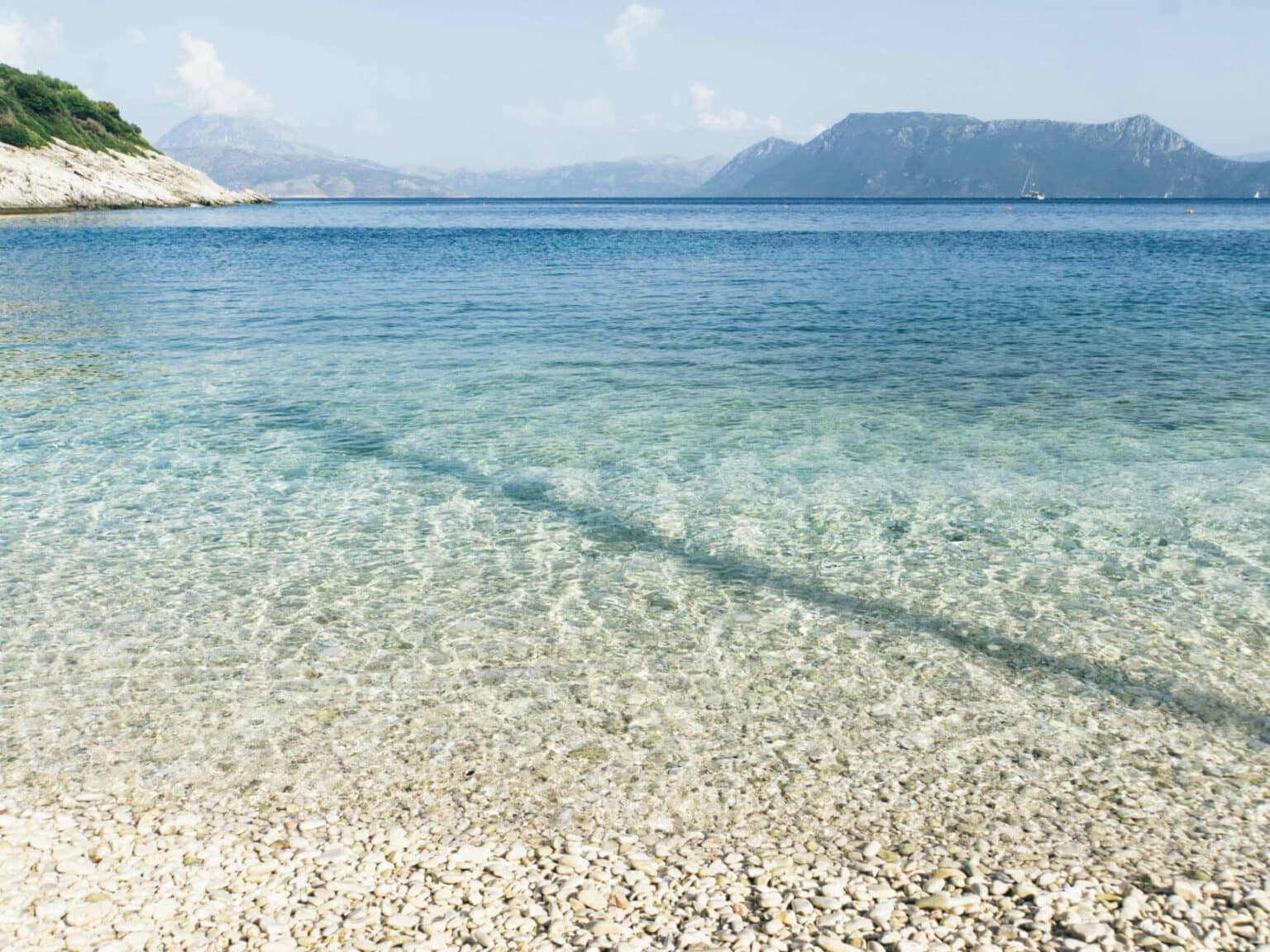 Glasklares Wasser am Kiesstrand von Meganisi, der kleinen Nachbarinsel von Lefkada im Ionischen Meer.