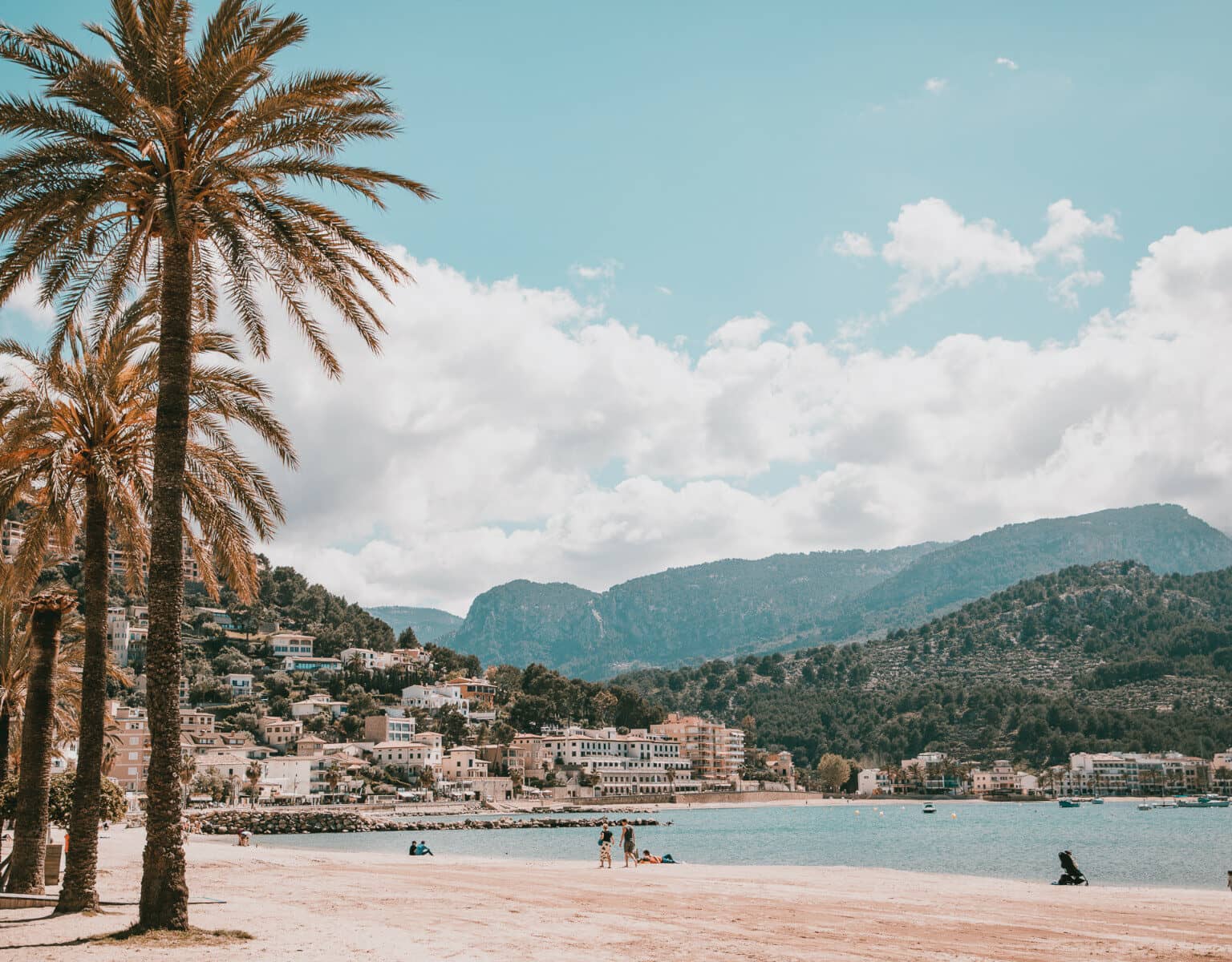 Der Strand mit Palmen am Port de Sóller mit Bergpanorama im Hintergrund.