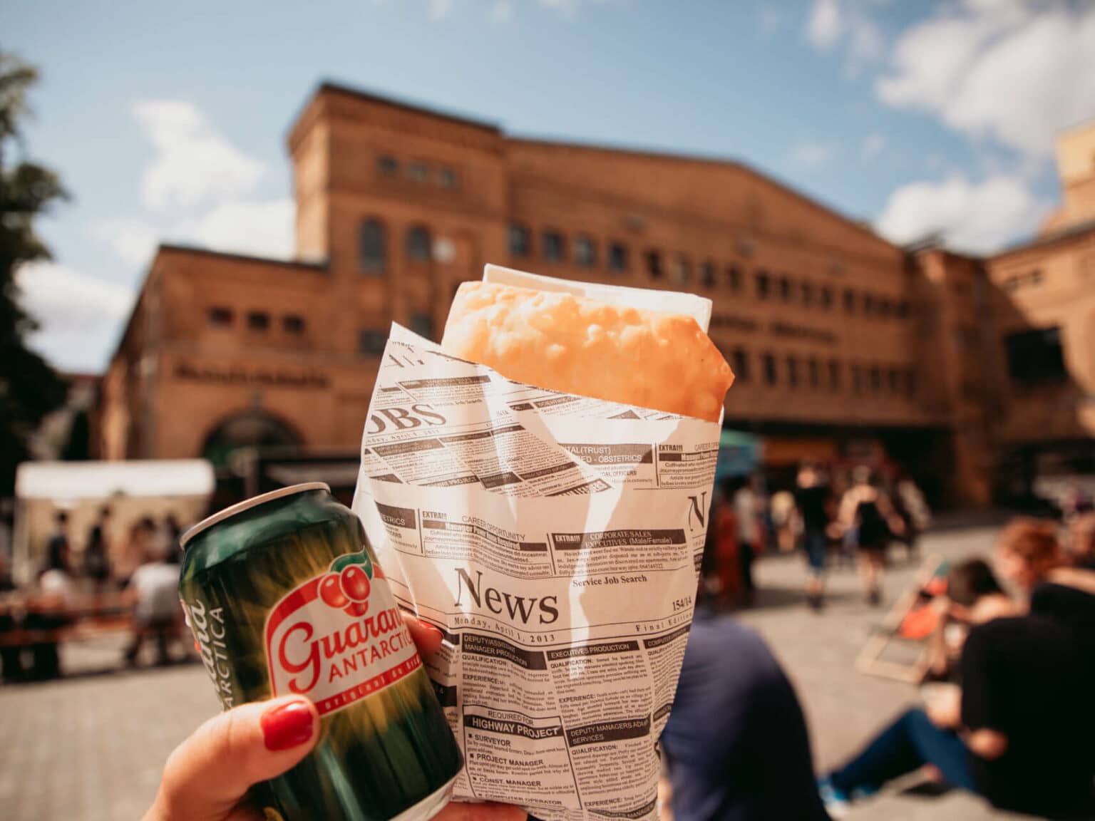Brasilianische Pasteis und Guaraná werden vor der Kulturbrauerei hochgehalten.