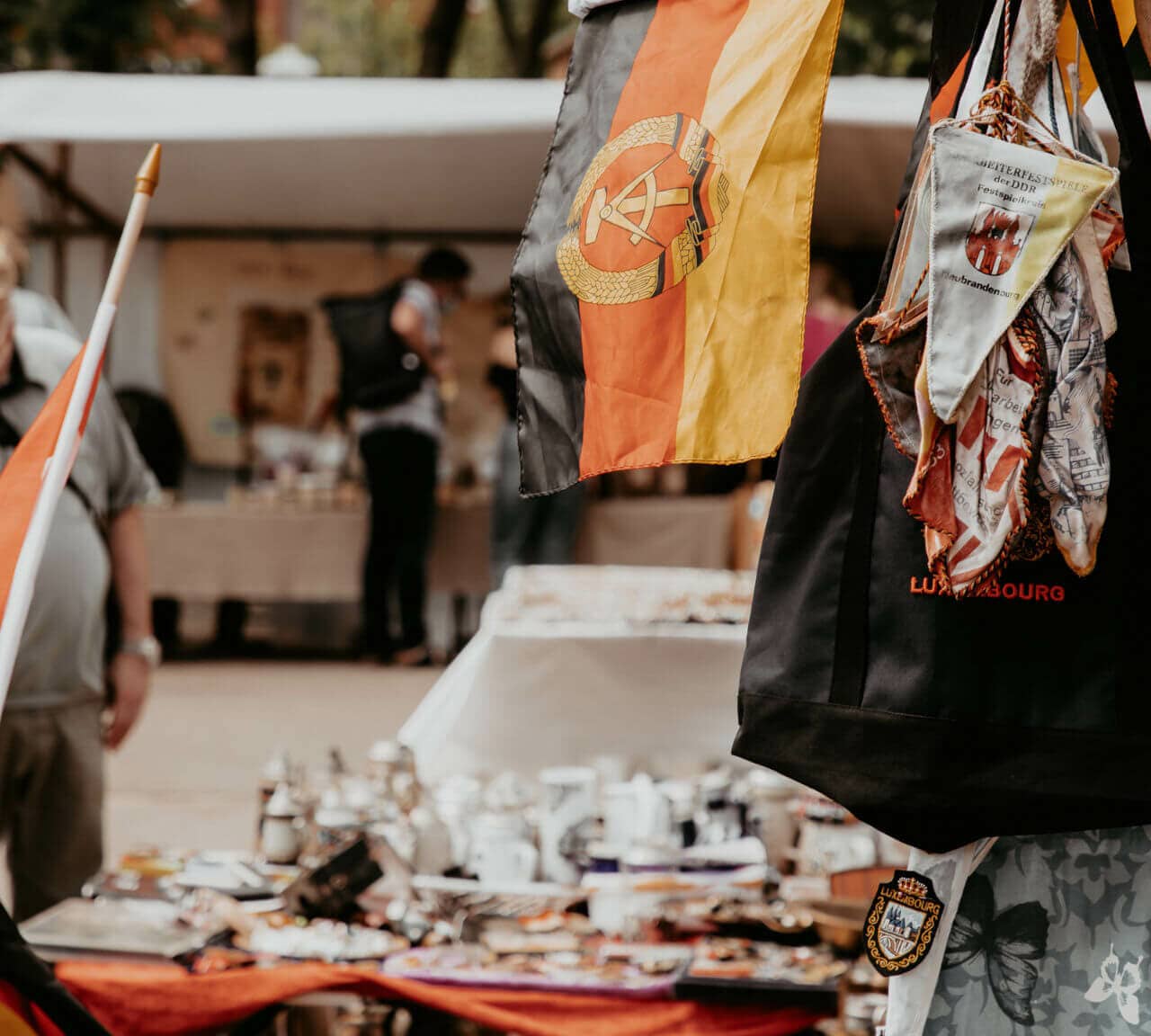 Ein Stand mit allerlei Gegenständen und alter DDR Fahne auf dem Mauerpark-Flohmarkt in Berlin.