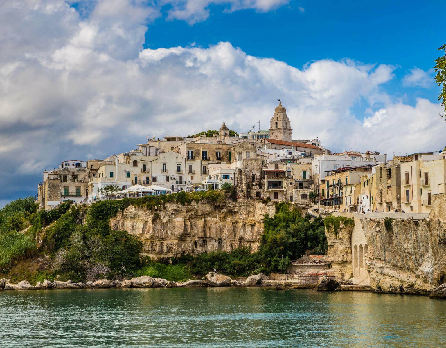 Vom Meer aus blickt man auf das Dorf Vieste in Apulien, das auf der Halbinsel Gargano im Abendlicht liegt.