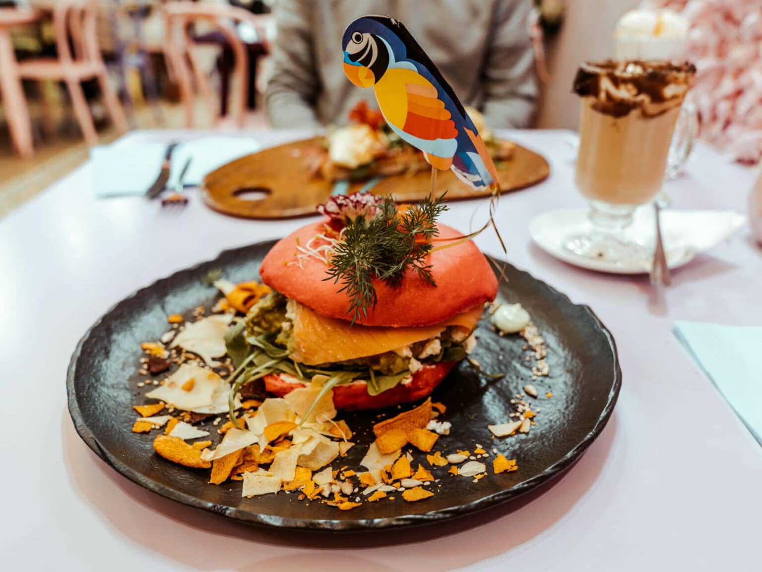 Bei der Eixampeling Brunch Café & Bar in Barcelona türmen sich beim The Smashed Avo Avocado, Feta, Rucola, Nüsse und auf Wunsch ein pochiertes Ei auf einem Red Velvet Bagel.