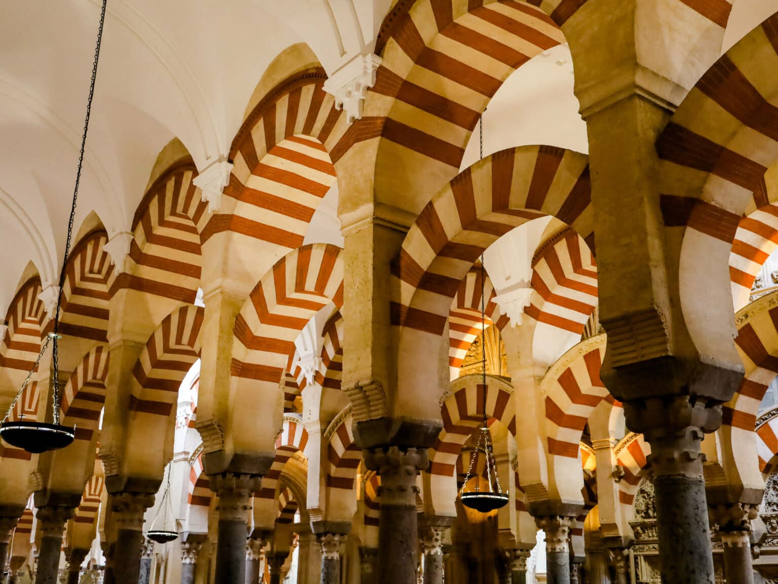 Beindruckende rot-weiß verzierte Rundbögen-Architektur findet man in Cordoba in der Mezquita.