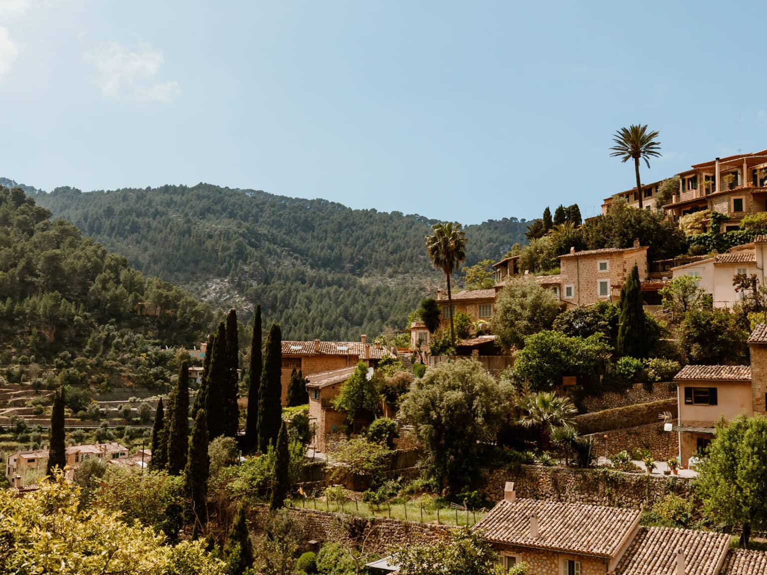 Mallorquinische Steinhäuser in Serra Tramuntana umgeben von einer grünen Berglandschaft.