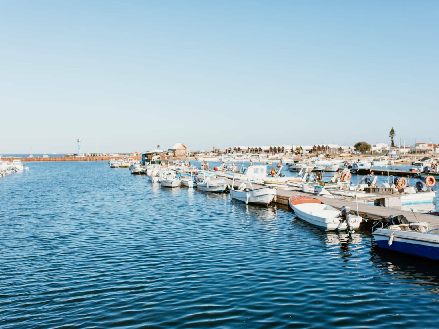 Den Hafen auf der Ilha Culatra in Faro schmücken Boote und blaues Wasser.