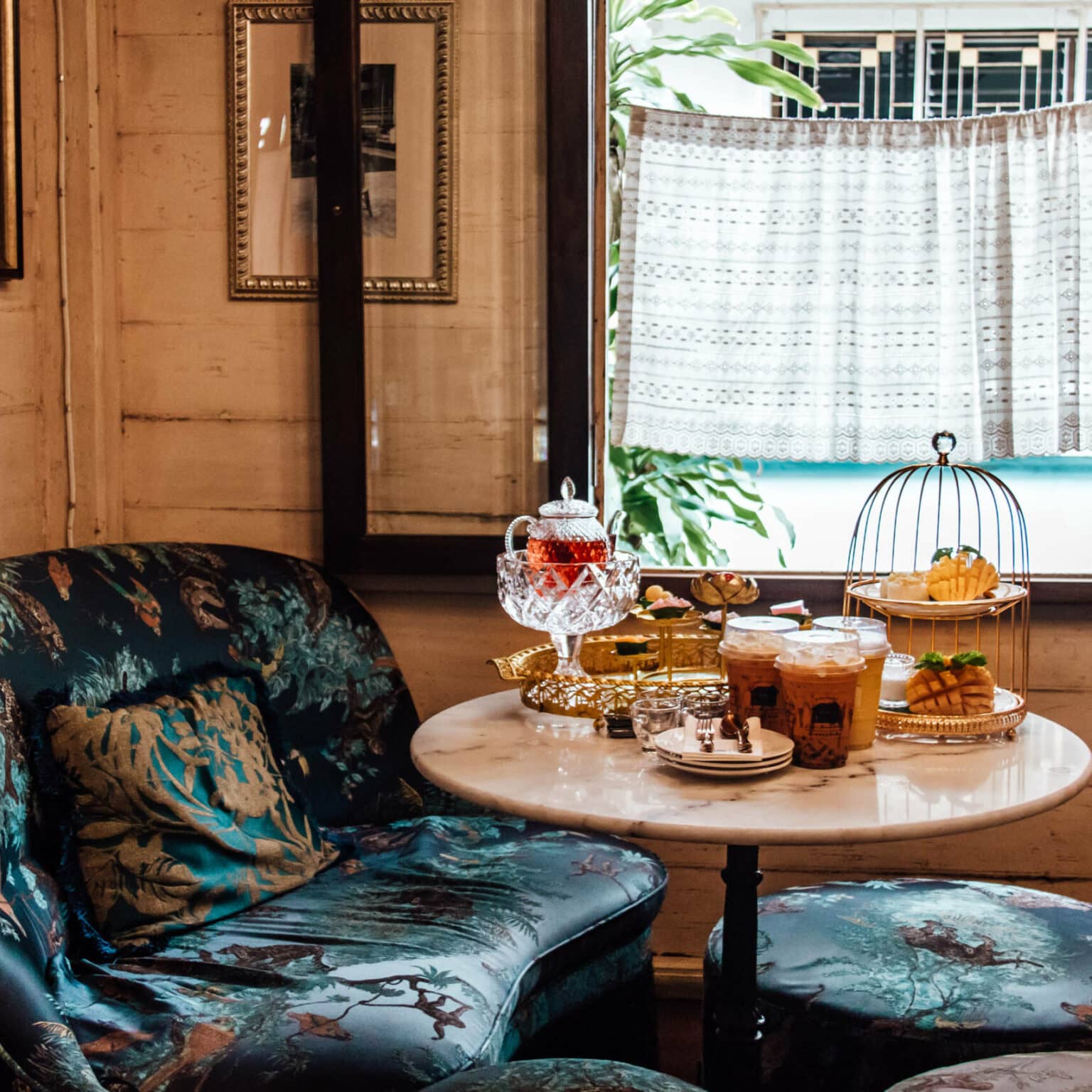 Ein Tisch im Gingerbread House auf dem thailändisch Teespezialitäten stehen umgeben von petrolfarbenen Couchmöbeln.