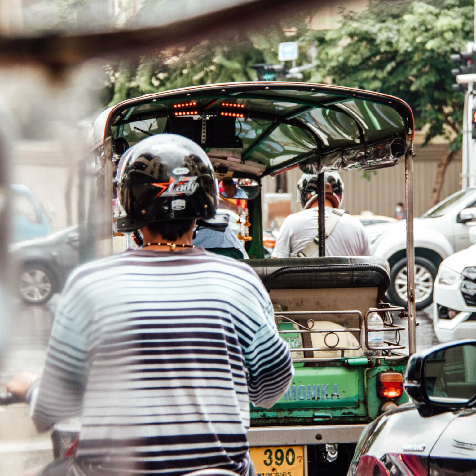 Tuk Tuks und Einheimische auf Rollern schlängeln sich durch Bangkoks Straßenverkehr.