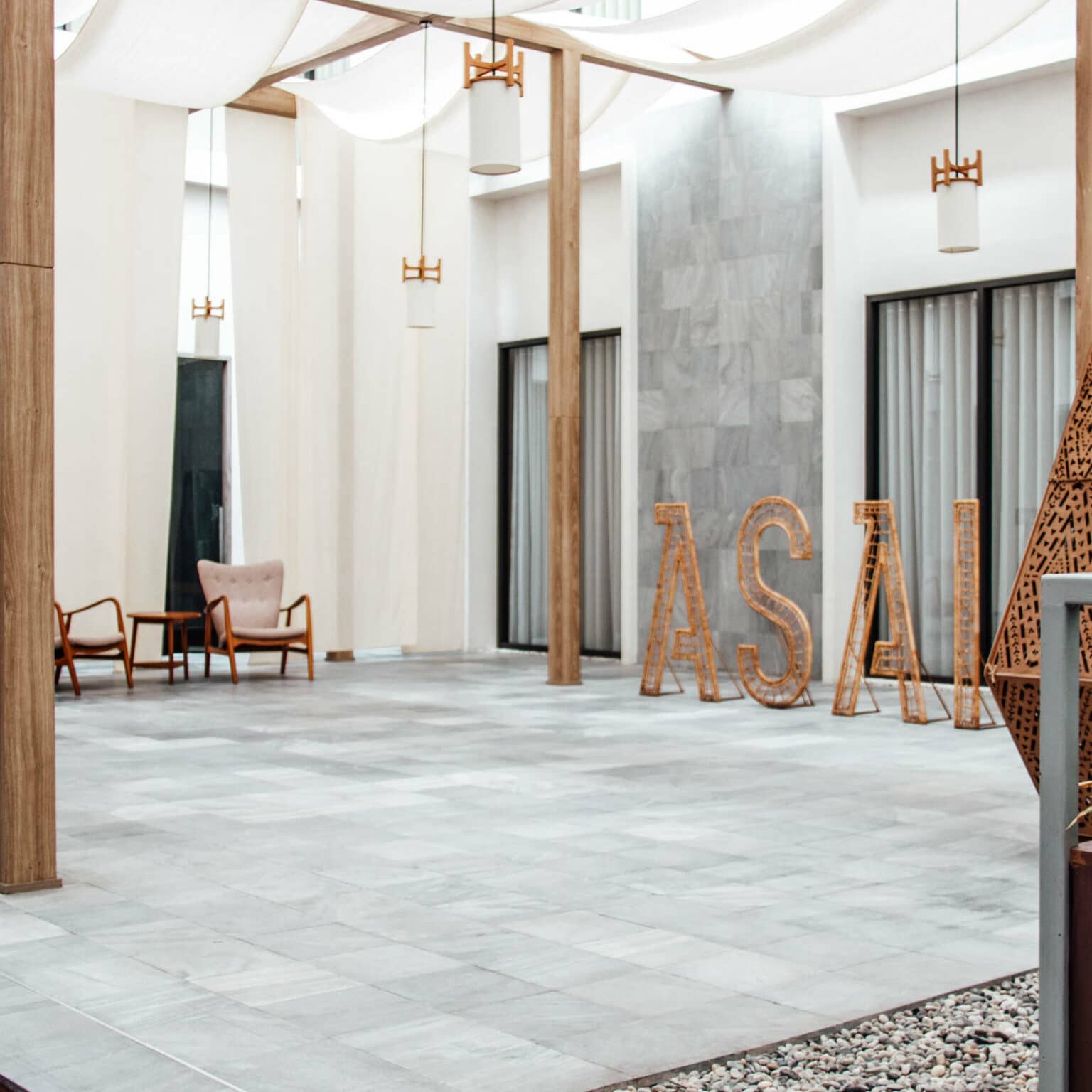 Das moderne ASAI Hotel in Chinatown von Bangkok mit grauen Wänden und weißen Tüchern die von der Decke hängen.