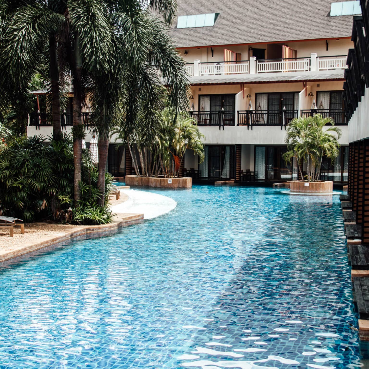 Der Pool des Chada Lanta Beach Resort umgeben von Liegen unter Palmen angrezend an die Zimmer.