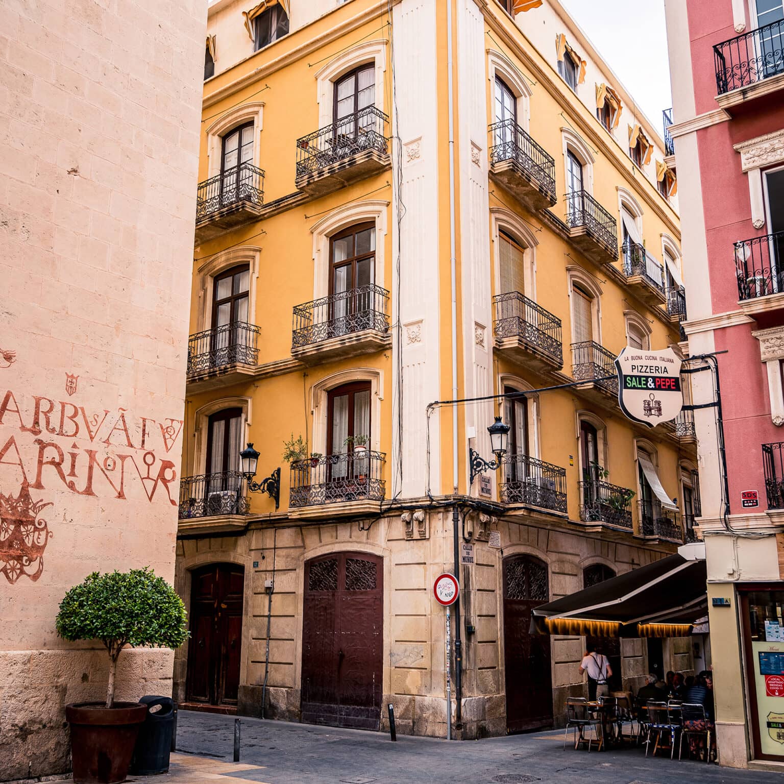 Ein gelbes älteres Haus mit Balkonen und Holztüren in Alicante.