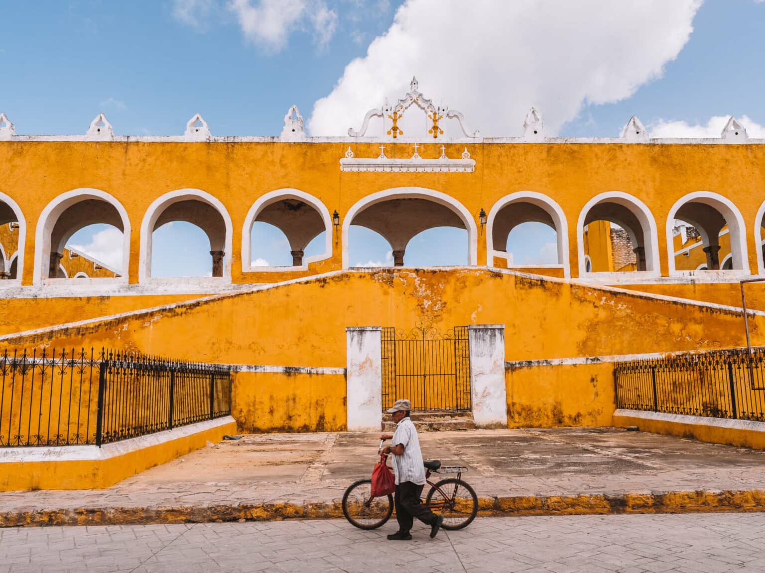 Ein Mann mit Fahrrad vor der gelben Stadt Izamal.