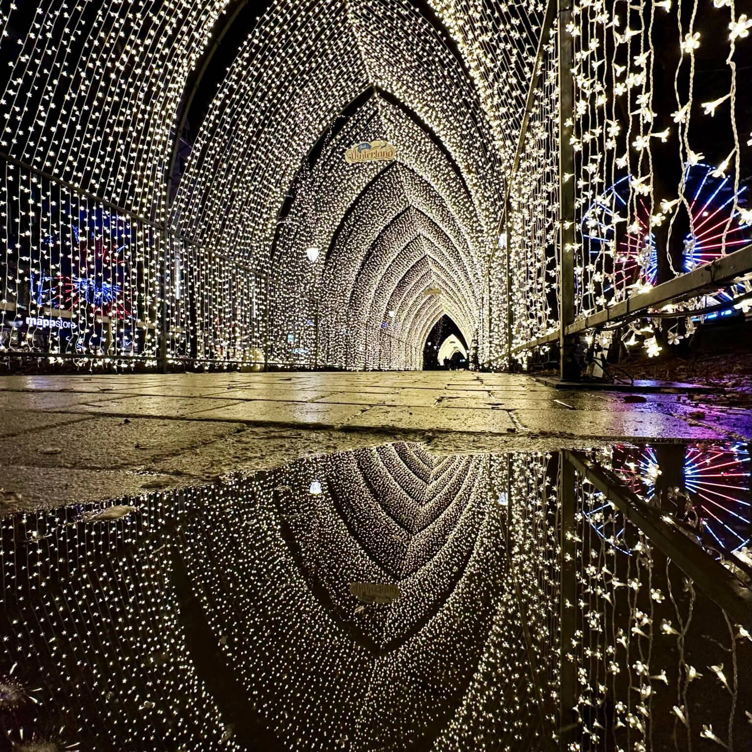 Der Lichtertunnel aus vielen weiß leuchtenden Lichterkettenauf dem Weihnachtsmarkt in Oslo bei Nacht.