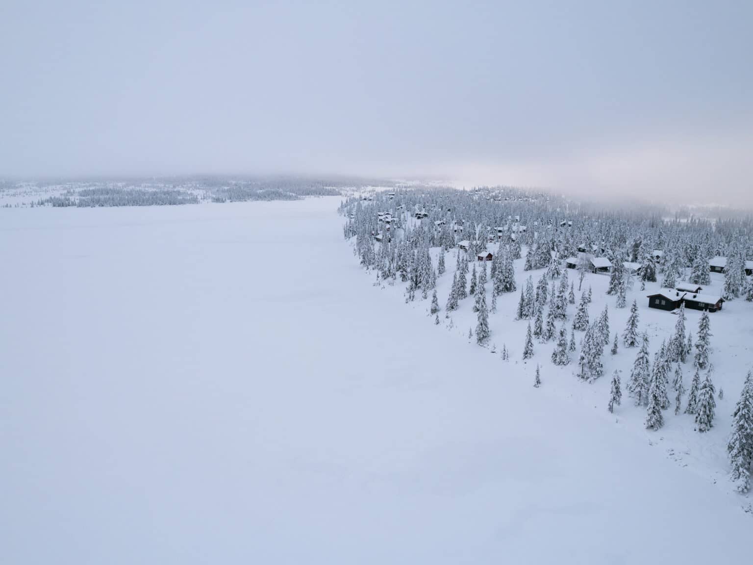 Ein zugefrorener und verschneiter See in der Winterlandschaft in Sjusjøen