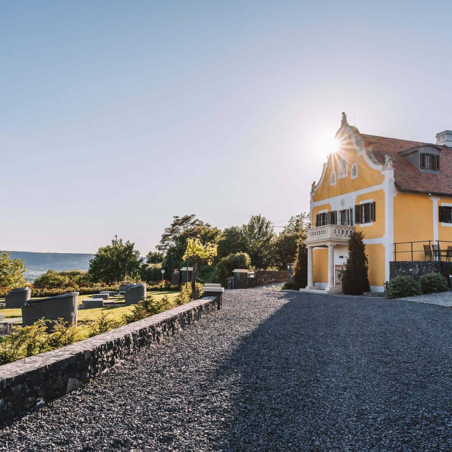 Ein Kiesweg führt zu dem gelben Haus des Weinguts in Balaton.