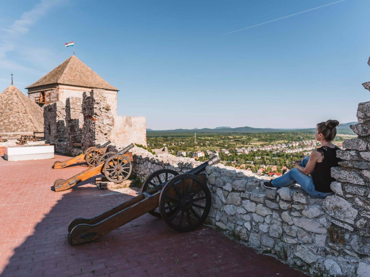 Bloggerin Melanie sitzt auf der Steinmauer der Burg Suemeg in Ungarn und schaut in die Ferne.