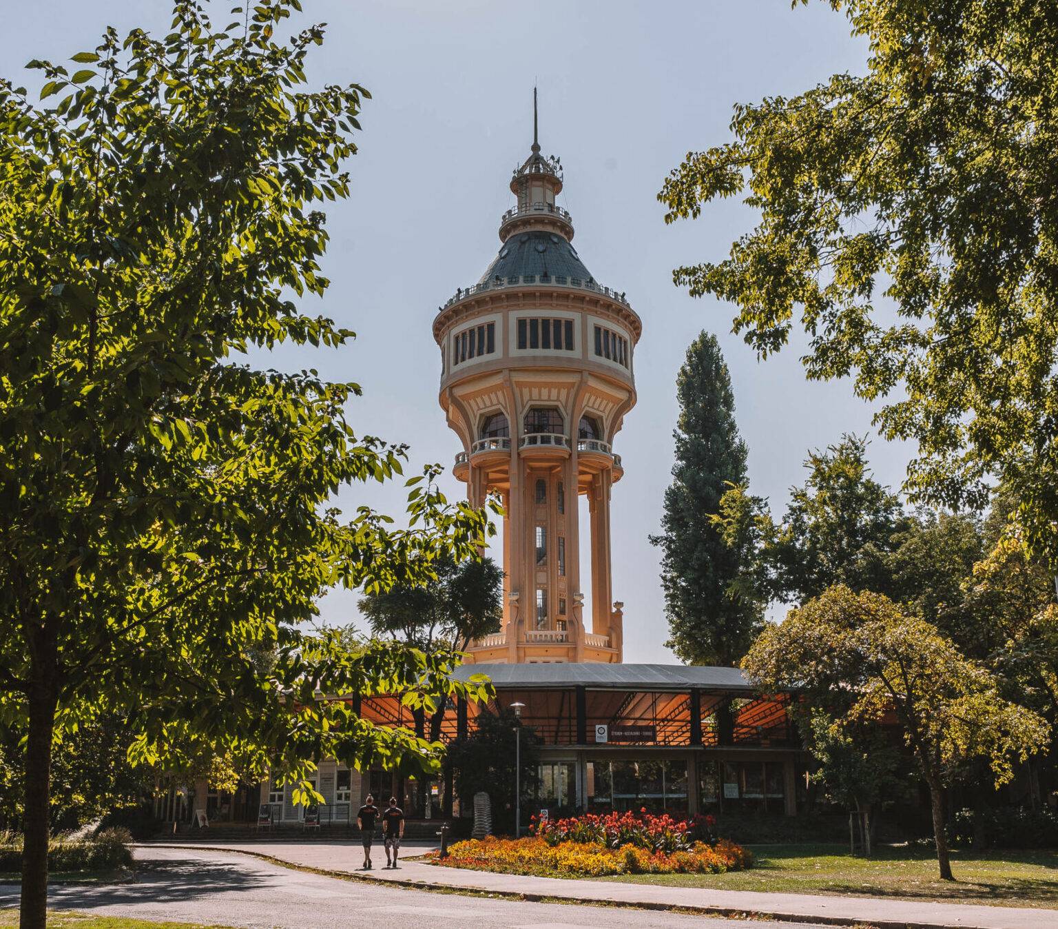 Der Wasserturm auf der Margareteninsel in Budapest umgeben von Bäumen.