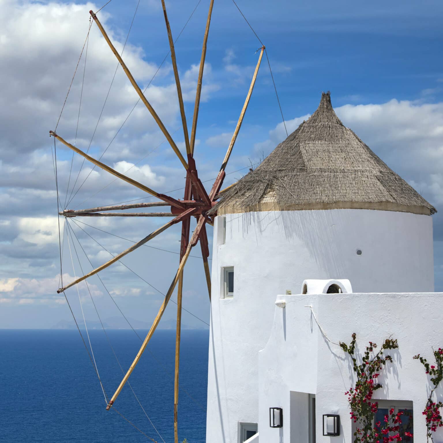 Eine weiße alte Windmühle mit Blick aufs blaue Meer in Griechenland.