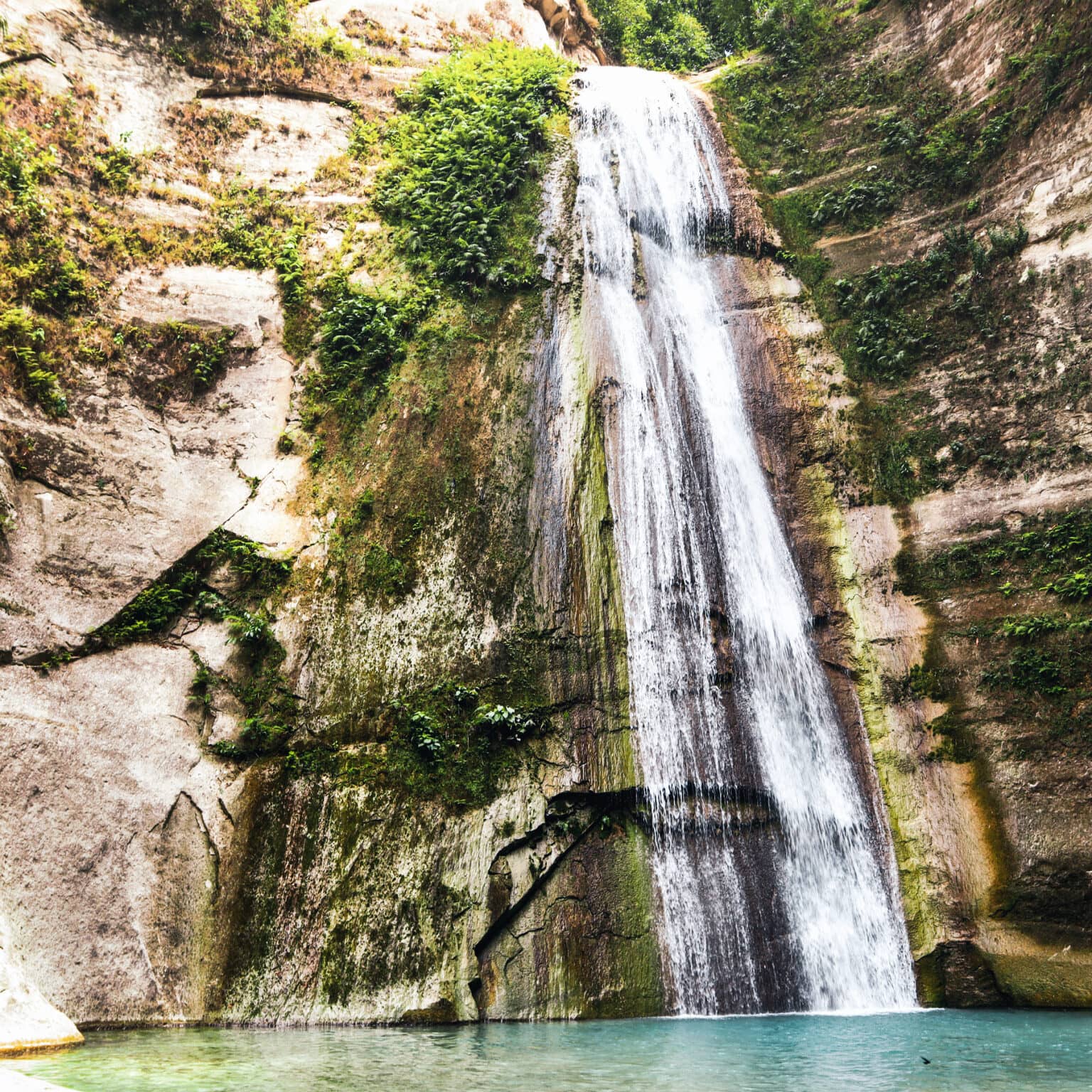 ein großer Wasserfall fließt einen hohen Felsen hinunter.