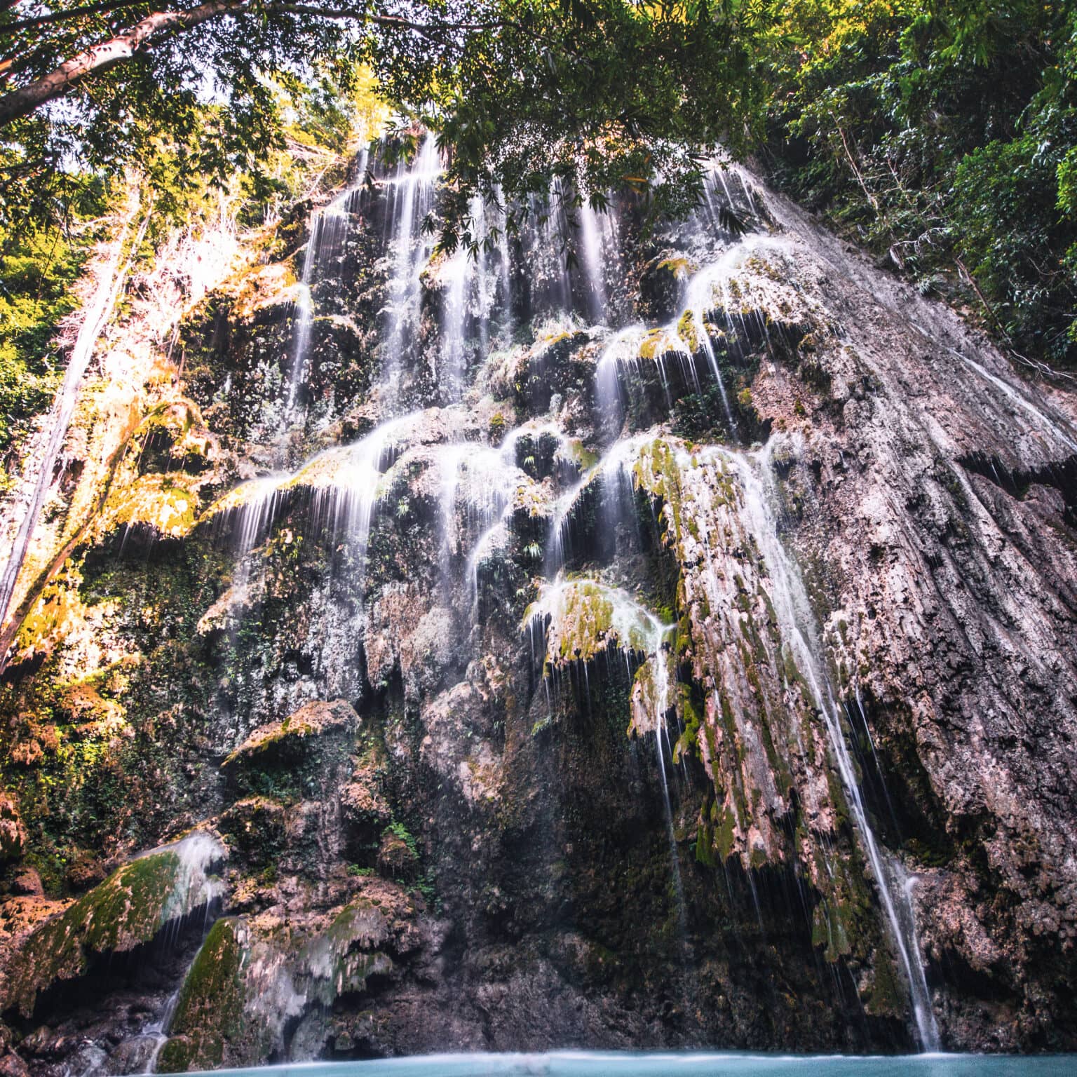 Das Wasser des Wasserfalls fließt über diverse Felsvorsprünge die Klippe hinunter.