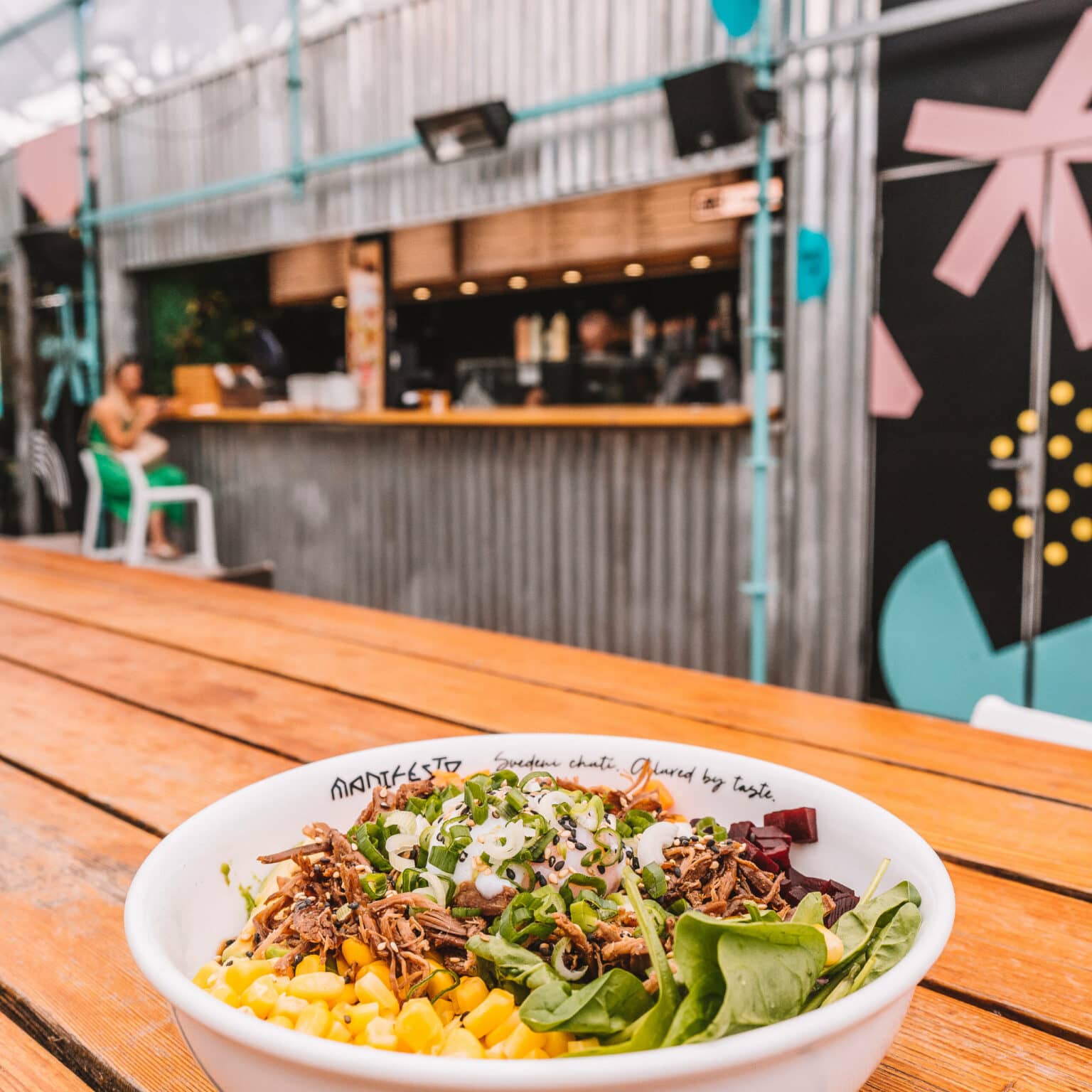 Eine Pokebowl auf einem Holztisch auf dem Manifesto Anděl Food Market in Prag.