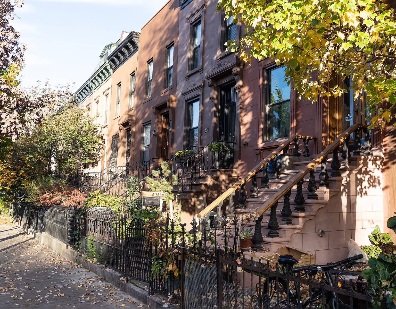 Die Brownstone Houses, ein Wahrzeichen von Brooklyn, sind Reihenhäuser in verschiedenen Brauntönen mit kleine Gärten und Treppen die zu den Häusertüren führen.