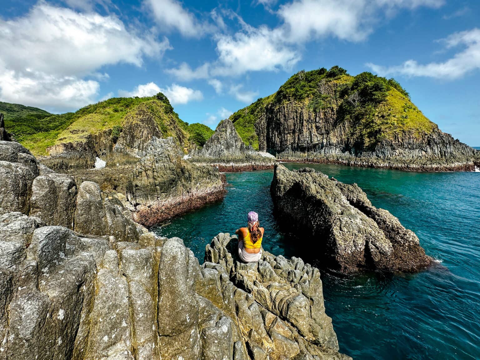 Reisebloggerin Nina von Traveloptimizer sitzt auf einem Basaltfelsen beim Semeti Beach, einem Strand auf Lombok.