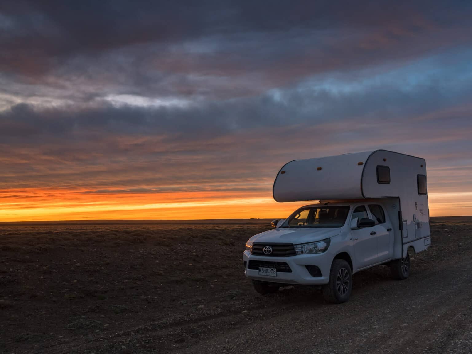 Ein Pickup-Camper auf einer Straße in Chile im Abendlicht.