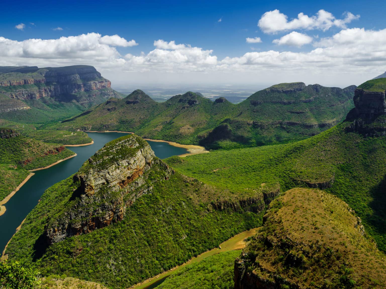 Der Fluss Blyde River Canyon schlängelt sich durch die Landschaft an hohen Felsen vorbei.