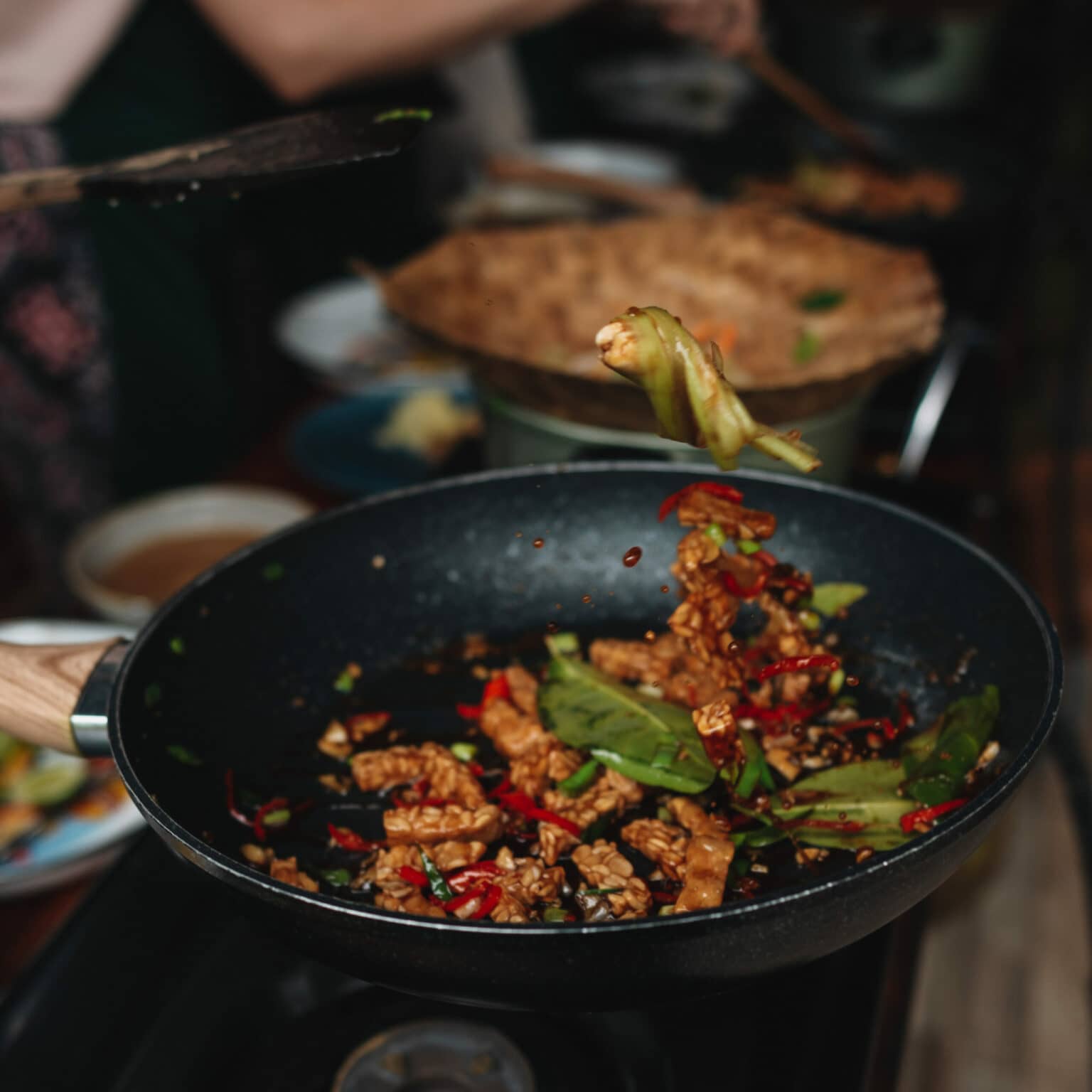 In einer Pfanne wird verschiedenes Gemüse und Temphe, typische Küche für Bali, gebraten.